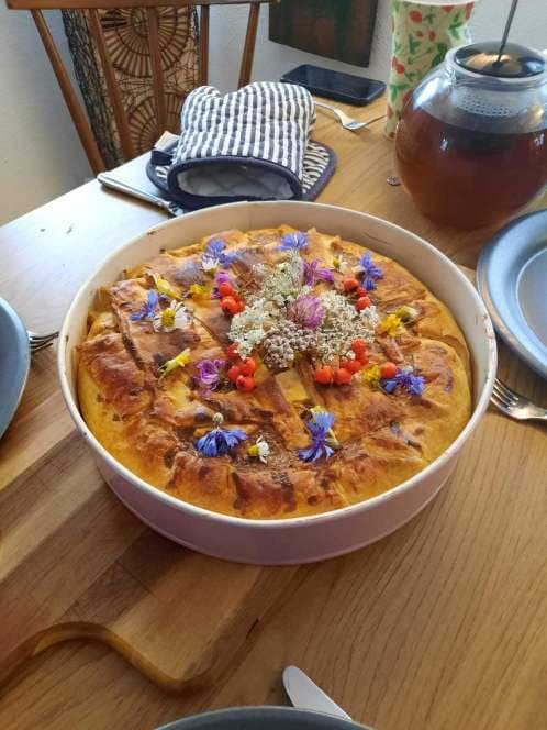 Kuchen dekoriert mit Wildblumen und Kraeutern
